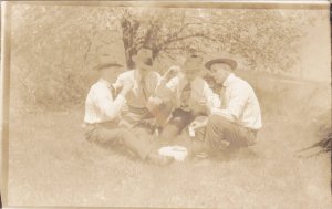 RP; Four men playing cards out in a field, 1910s