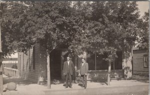 RPPC Two Men Typical Neighborhood Corner Store Auto Shop in Distance Postcard X2