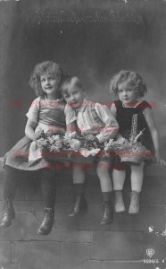 Studio Shot, RPPC, Three Children Sitting on a Wall Holding Baskets of Flowers