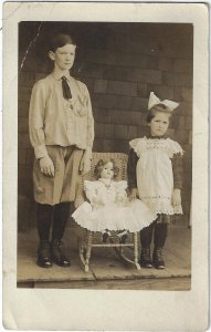Doll in Dress, Wicker Chair w/ Standing Girl  & Boy RPPC Real Photo Postcard