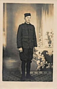 YOUNG MAN IN MILITARY UNIFORM ?~BRIMLESS HAT-REAL PHOTO POSTCARD