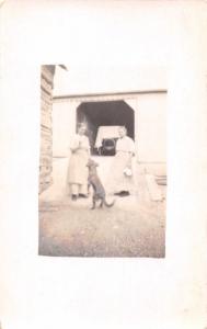 TWO WOMEN PLAY WITH BLACK DOG~OLD CAR IN SHED REAL PHOTO POSTCARD 1900s