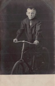 YOUNG BOY-MILITARY? LOGO ON TIE-SITTING ON BICYCLE~1910s REAL PHOTO POSTCARD