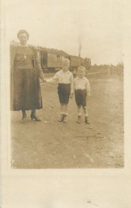 children types Social History Postcard mother with young boys next to train