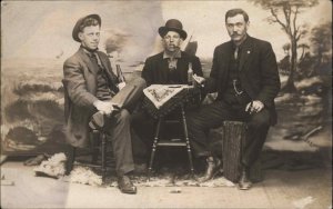 Men in Studio Gambling Drinking Bottle Cigar Playing Cards Real Photo Postcard