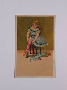 Victorian Trade Card Little Girl Putting on Pink Stockings