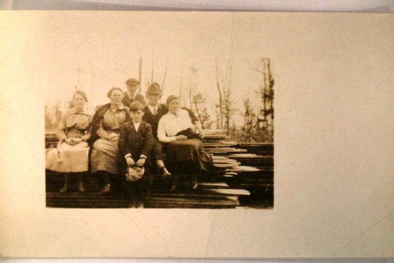 pre-1918 rppc FAMILY SITTING ON PILE OF WOOD & LUMBER unusual postcard y3926