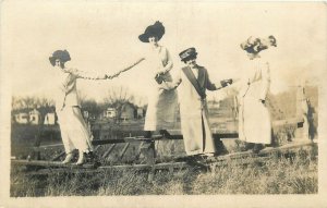 Postcard RPPC C-1910 Pretty Women big hats fashion standing on fence TP24-2347