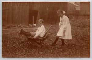 RPPC Victorian Children Girl with Boy in Wheelbarrow on the Farm Postcard C22