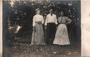 VINTAGE POSTCARD GROUP OF MAN AND TWO WOMEN REAL PHOTO ON DIVIDED BACK CARD