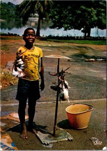 VINTAGE CONTINENTAL SIZE POSTCARD YOUNG FISHMONGER AT THE LAGOON ABIDJAN AFRICA