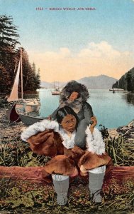 ESKIMO WOMAN & CHILD Sitting On Log In FUR & BOOTS Boats Behind c1910's Postcard
