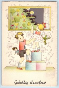 c1930's Christmas Children With Doll Christmas Tree Wall Design Vintage Postcard