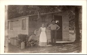 Real Photo Postcard Man and Woman Outside Tiny House or Cabin