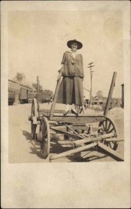 Woman Stands on Old Wagon Wheels Axles Visible c1910 Real Photo Postcard