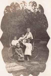 LOTS OF KIDS CHILDREN AROUND A BICYCLE ~1910s REAL PHOTO POSTCARD