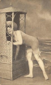 WOMAN IN BATHING SUIT AT BEACH WICKER FURNITURE RISQUE POSTCARD (c. 1910)