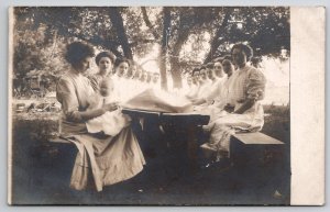 RPPC Group of Victorian Women Lined Up Seated at Picnic Table Postcard L40