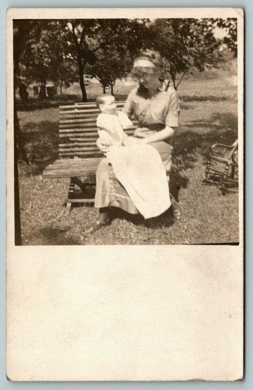 RPPC Young Lady on Bench Holds Realistic-Looking Baby Boy Doll on Her Lap c1910 