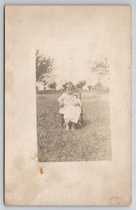 RPPC Cutest Little Girl Seated with her China Head Doll in Yard Postcard H30