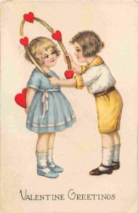 Valentine Greetings Boy Places Heart Horseshoe over Girl 1919 postcard