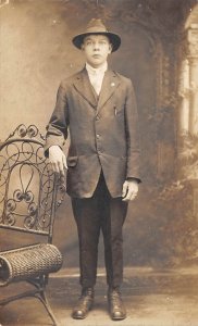 c1908 RPPC Real Photo Postcard Boy In Suit And Hat Standing Wicker Chair