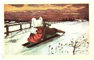 Boy pushing girl on sled down snowy hill New Year Postcard