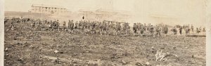 UNITED STATES WW1 SOLDIERS WORK IN FIELD IN FRONT OF BARRACKS-RPPC POSTCARD