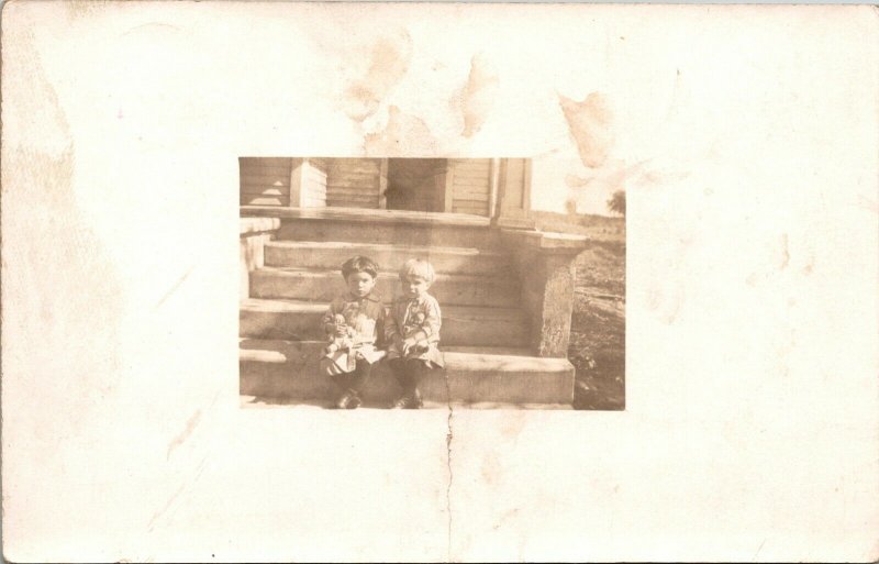 RPPC Two children girls sitting on steps dolls, Roe Studio, Iowa Winter Family 