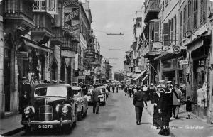 (Busy) Main Street, Gibralter Postcard. Cars, Sailors, Storefronts, Watch Sign