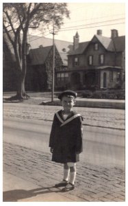 Girl in sailor suit, standing on curb