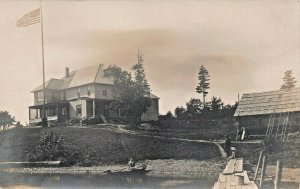LARGE HOUSE ON WATER-ROW BOAT-DOCK-AMERICAN FLAG~1910s REAL PHOTO POSTCARD