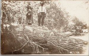 Man and Woman Standing on Large Tree Cut Automobile Real Photo Postcard G75