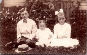 Real Photo Postcard Three Well Dressed Children Sitting Outside in Garden