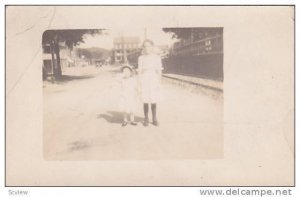 RP; Two girls standing on middle of street, smaller girl covering eyes, PU-1912