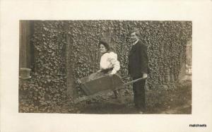 Circa 1906 Woman in Wheel Barrow Ivy Wall RPPC postcard 15001