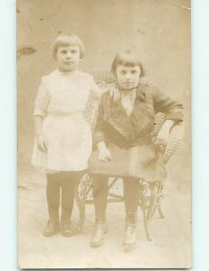 Pre-1918 rppc GIRL WITH BUTTON SHOES IN ANTIQUE RATTAN CHAIR r5957