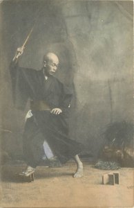 Hand-Colored Japanese Postcard; Man Loses one of his Geta Shoes, Waves a Stick