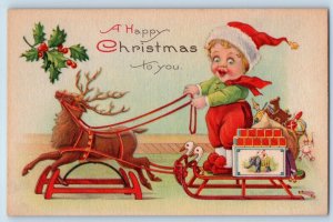 Christmas Postcard Little Kid Playing Deer Sleigh With Toys Holly Berries c1910s