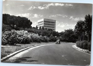 Old car driving down road with Palazzo Della Civiltà in background Rome Italy