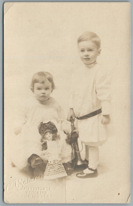 LITTLE GIRL & BOY w/ LARGE DOLL 1912 ANTIQUE REAL PHOTO POSTCARD RPPC