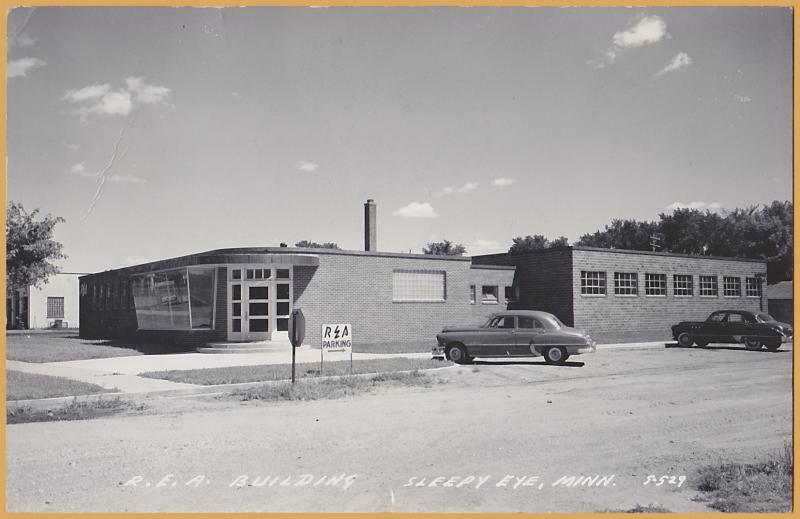 RPPC-Sleepy Eye, Minnesota - R.E.A. Building with 1950's autos out front - 1953