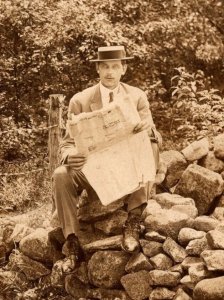 RPPC  Man Sitting on Rock Wall Reading Real Estate Newspaper Real Photo  c1910