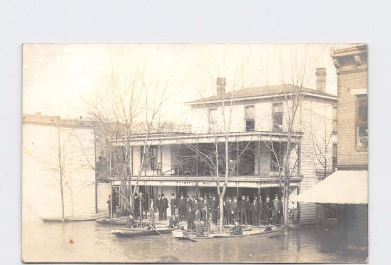 RPPC REAL PHOTO POSTCARD FLOOD MEN GATHERED ON PORCH OF HOTEL BRIT BOATS DOCKED 