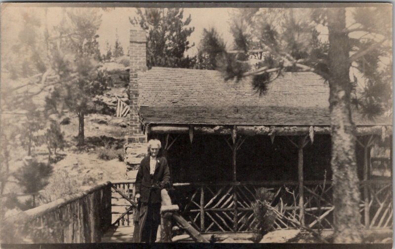 RPPC Old Woman on Porch Old Log Cabin Pine Trees Real Photo  Postcard Y1
