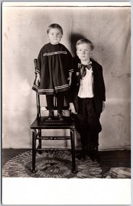 Siblings Big Boy And Little Girl Standing On Top Of The Chair Postcard