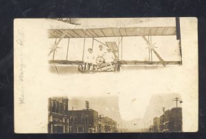 RPPC WOMEN IN BIPLANE OVER DOWNTOWN STREET SCENE REAL PHOTO POSTCARD