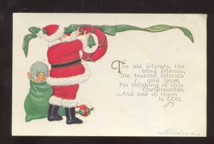 SANTA CLAUS RED ROBE PUTTIN UP WREATH VINTAGE CHRISTMAS POSTCARD 1910
