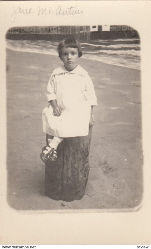 RP; Little girl wearing a white frock sitting on log stool, 1900-10s