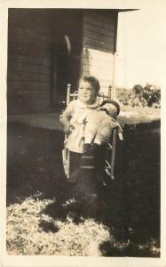 c1928 RPPC Toddler in Child's Rocking Chair w/ Raggedy Andy Type Doll Unknown US